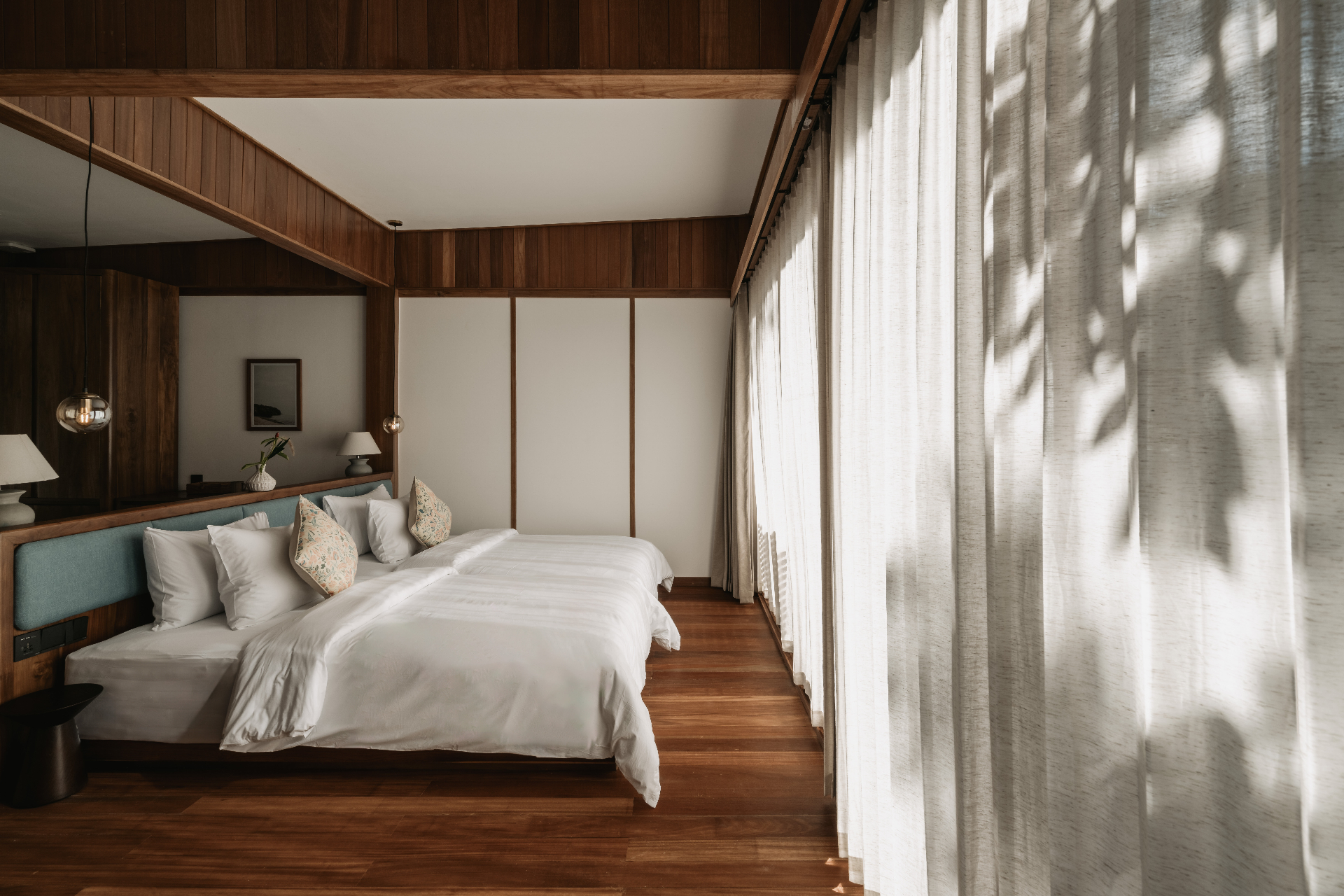 Warm timber bedroom with twin beds and filtered morning light
